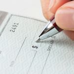 close up of hand and pen writing a check