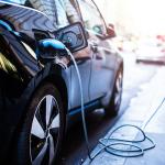 black electric car plugged into charger