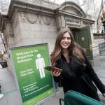 Teddy Siegel holding her phone while posing outside a Bryant Park Bathroom in New York City.