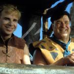 Actors Rick Moranis and John Goodman riding together in a scene from the 1994 film 'The Flintstones.'