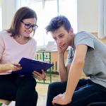 A woman counselor having a discussion with a teenage boy in school.