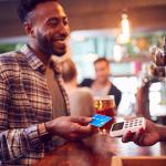 Person buying a drink from a bar with his credit card.