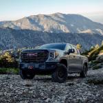 Grey 2023 GMC Sierra 1500 AT4X AEV Edition driving on a rocky hillside.