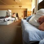 Men lying on beds in a homeless shelter.