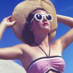 Person wearing sunglasses and a wide-brimmed hat sunbathing in 1944.