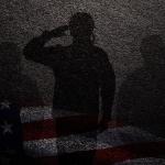 Concept of military sexual assault illustrated by three silhouettes against a dark wall, faint overlay of American flag beneath.