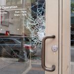 A store's glass door is cracking from damage.
