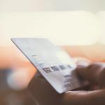 A vibrant background drawing focus on a hand holding a credit card.