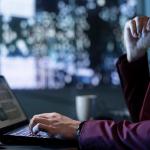Person looks at finance data on laptop with abstract background suggesting concept of technology and future.