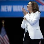 Democratic presidential nominee, U.S. Vice President Kamala Harris wearing white, greets the crowd as she arrives on stage at a campaign rally at the Enmarket Arena August 29, 2024 in Savannah, Georgia.