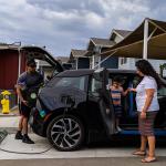 A family of three getting items ready inside a charging electric vehicle.