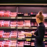 A woman shopping in the meat section of a supermarket.