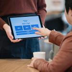 Cafe staff holding a tablet for additional tip options for customers.