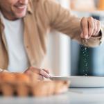 A man seasoning egg mixture with plenty of salt.