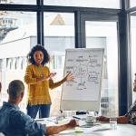 A woman facilitating a brainstorm session in a boardroom with a small team.