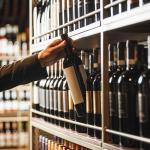 An extensive wine cellar collection and a wine bottle is being carefully picked.