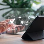 Business professional using a work table and holographic icons of standard employee insurance concepts are shown.