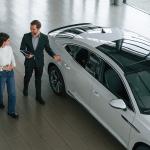 A woman choosing a new car in a dealership while an agent assists.
