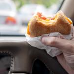 A breakfast sandwich being eaten inside the car during morning traffic.
