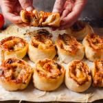 Pepperoni pizza rolls on a baking sheet.