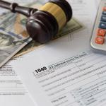 Tax law changes concept showing tax forms, bank notes, a calculator and a judge gavel.