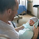 A father holding his newborn baby at the hospital a day after birth.
