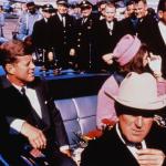 Texas Governor John Connally adjusts his tie as President John F. Kennedy and First Lady Jacqueline Kennedy settle into the rear seats of their car before the Dallas motorcade on November 22, 1963.