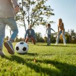 Kids playing soccer in park.