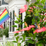 A rainbow pride flag and American flags affixed to a home.