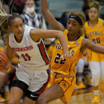 Two basketball players on a basketball court during girls basketball tournament. 