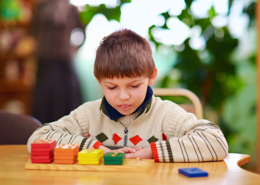 A young child studies stacks of colored blocks.