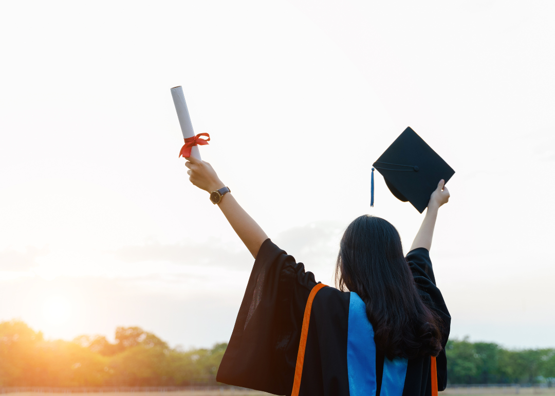 A graduate holding up her cap and diploma.