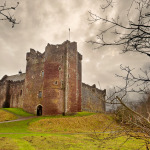 A castle made of gray stone with a number of towers, the tallest of which is in the center of the castle. 