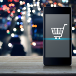 A shopping cart appears on a phone screen with city lights in the background.