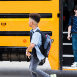 Young children exit a school bus. 