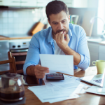 A man sitting at his kitchen table paying bills