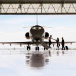 Silhouette of smaller aircraft with pilot and staff shaking hands and boarding.