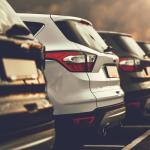 A line of small SUV's with ominous sky in background.