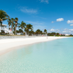 Homes on white sandy beach with crystal clear water.