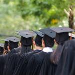College graduates in black caps and gowns in a line.