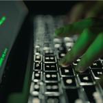 Fingers on a computer keyboard with dark background.