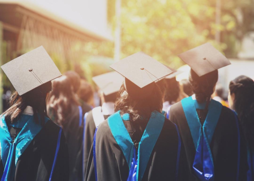 The backs of graduates in caps and gowns.