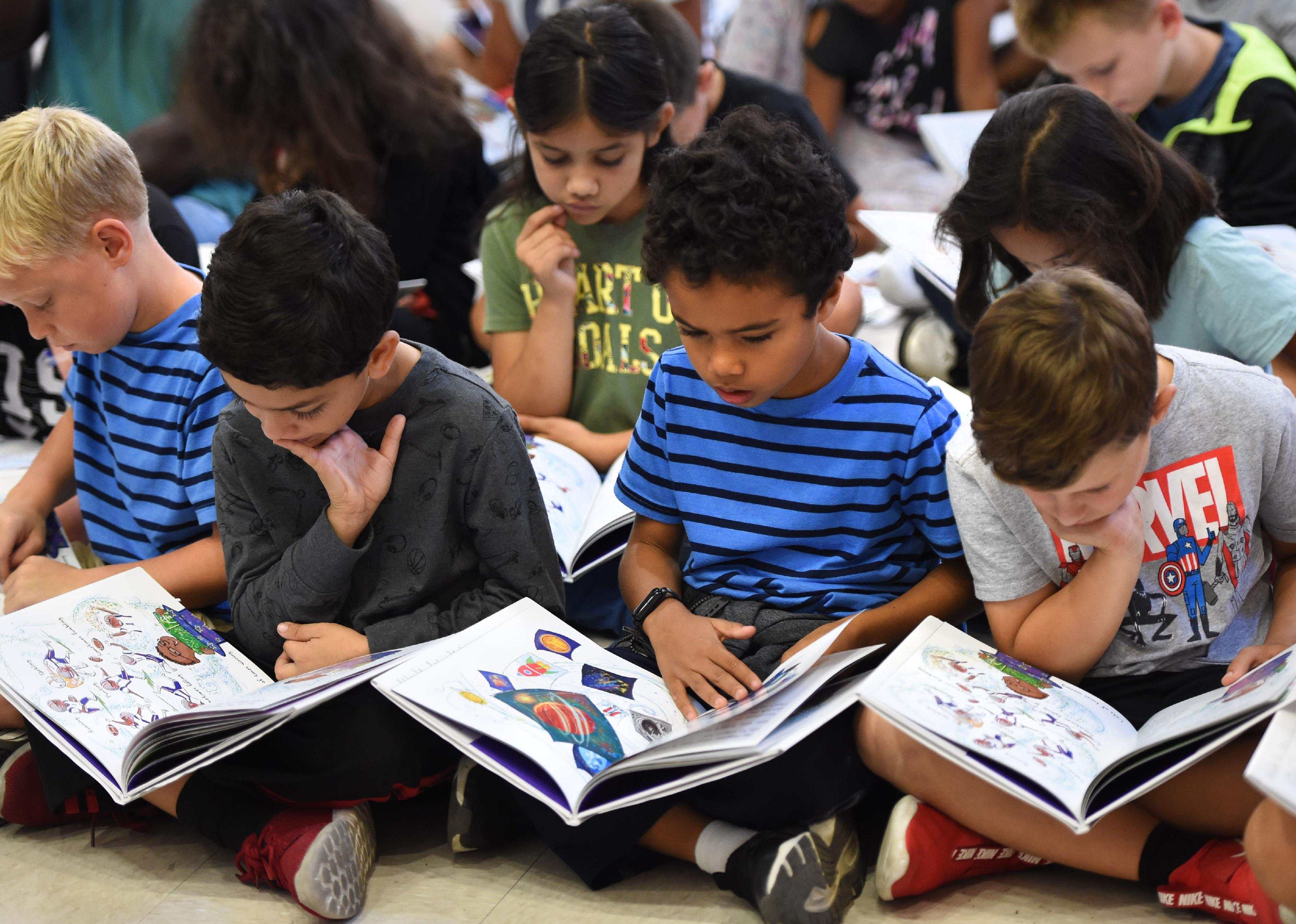 Kids sitting on the floor reading.