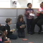 Kids sit and learn about money at a bank.