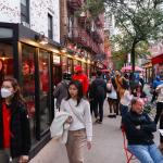 A busy New York sidewalk of people at restaurants.