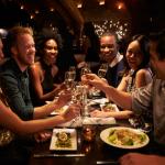 A group of friends toast each other at a restaurant.
