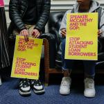 Students holding signs for student loan forgiveness.