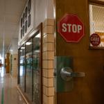 Almost empty hallway of a school with a stop sign on a door.