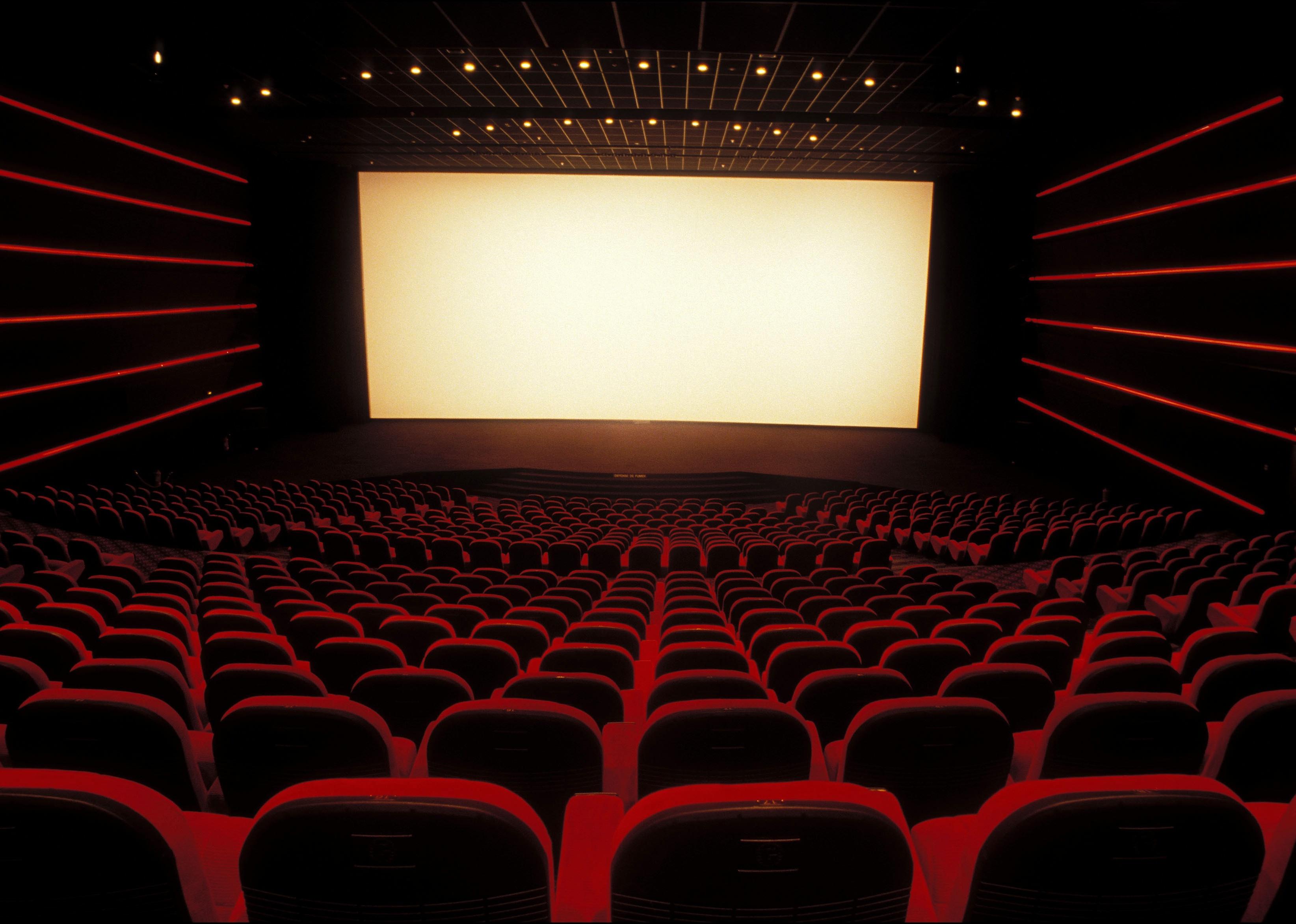 A beautiful empty movie theater with red seats and long red lights down the sides.
