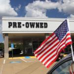 A used car lot with an American flag.